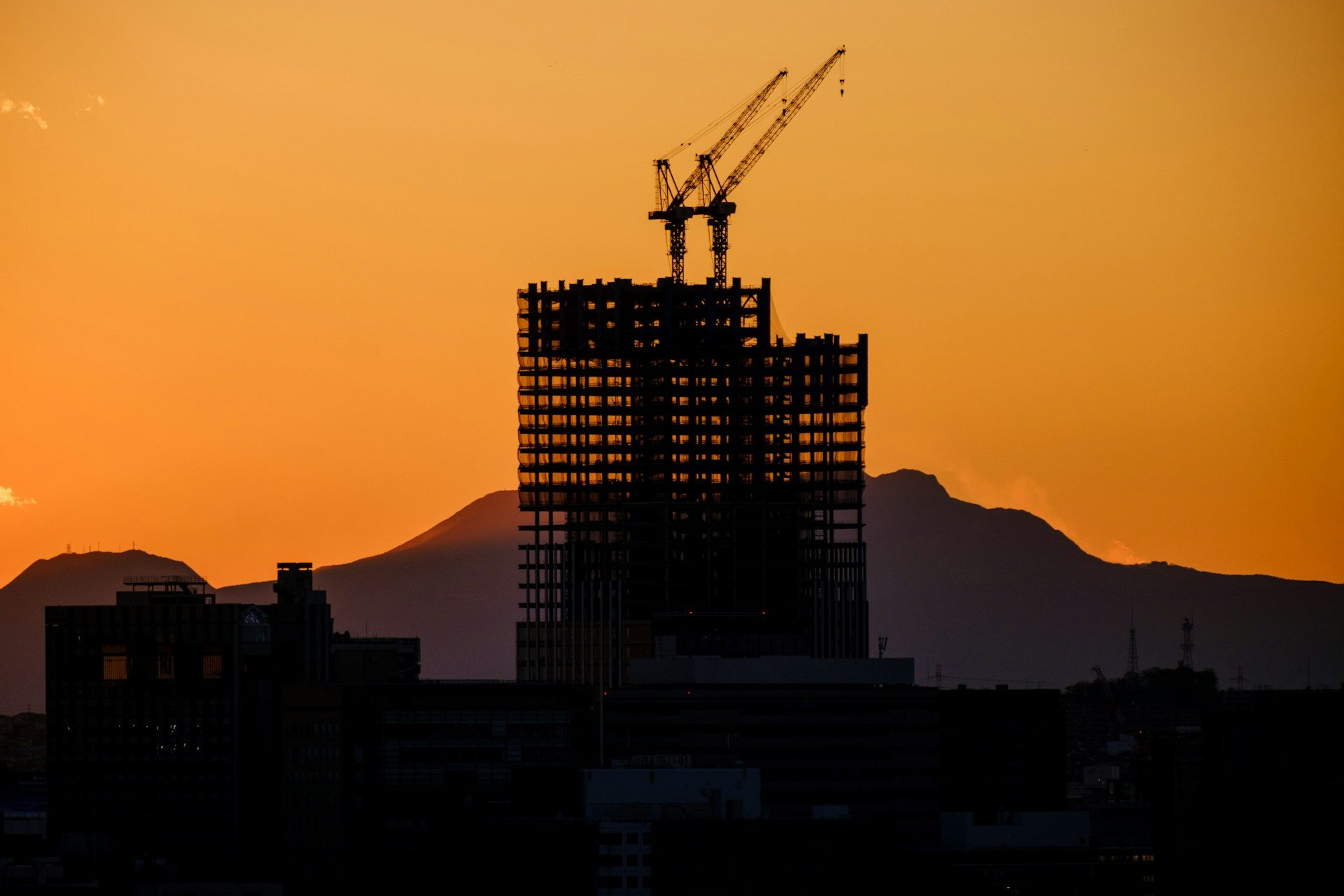 A building under construction with the sun setting in the background