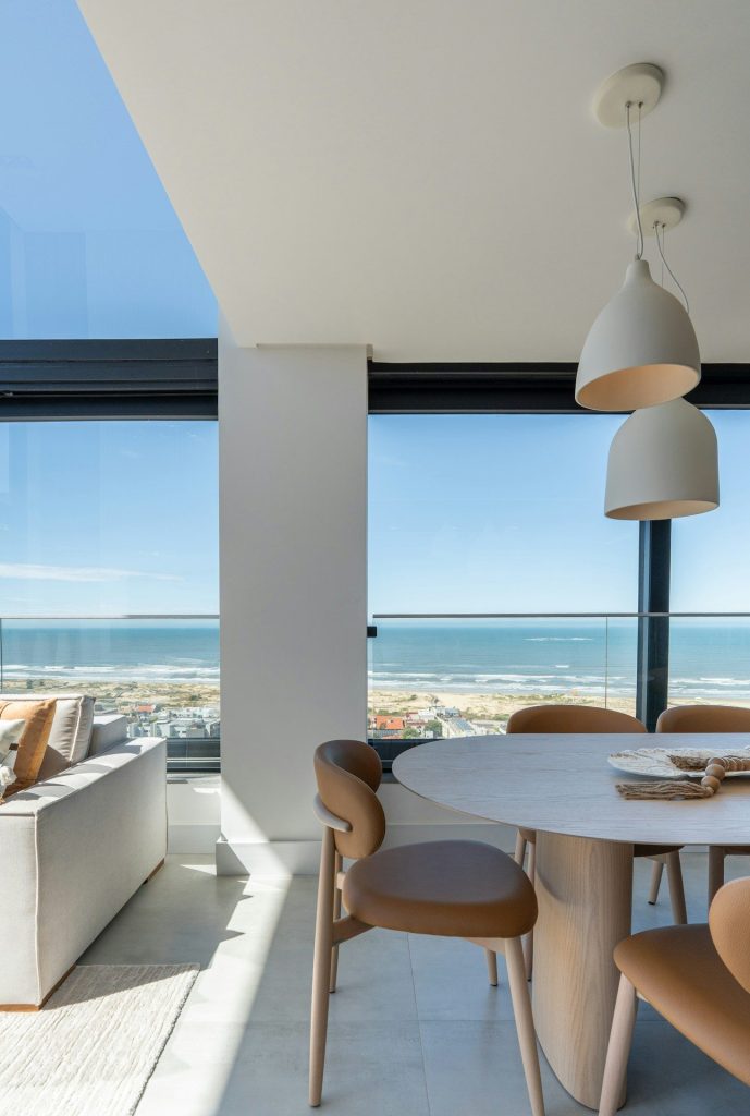 Modern dining area with ocean view through large windows.